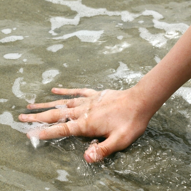 Hand-in-Wasser-und-Sand-getaucht