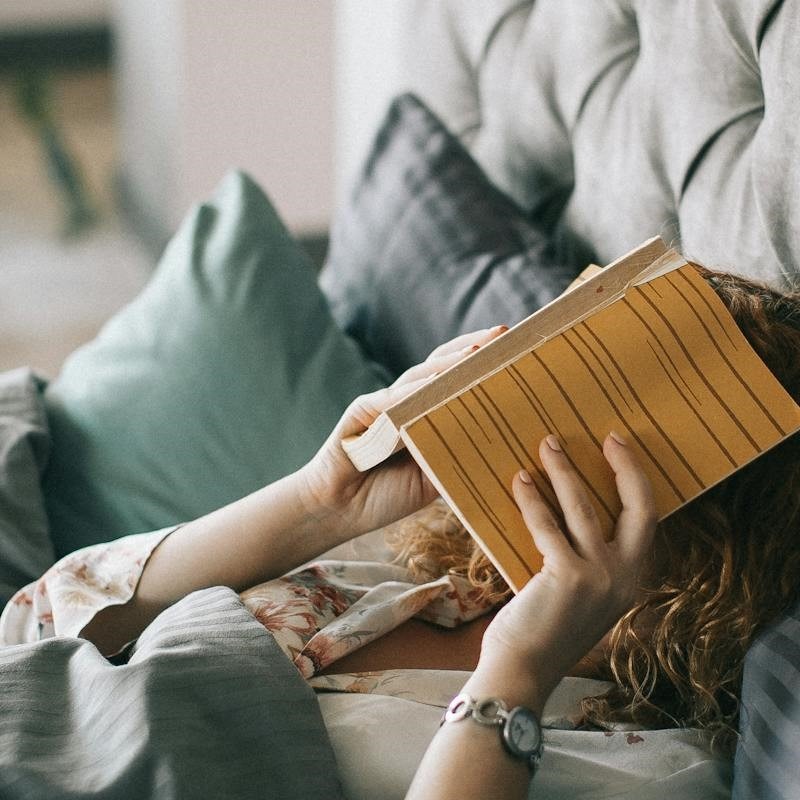 frau-liegt-im-bett-und-haelt-buch-vor-gesicht