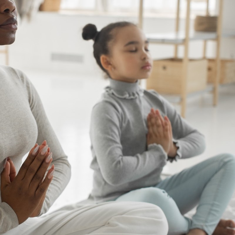 frau-macht-mit-kind-am-boden-eine-yoga-uebung
