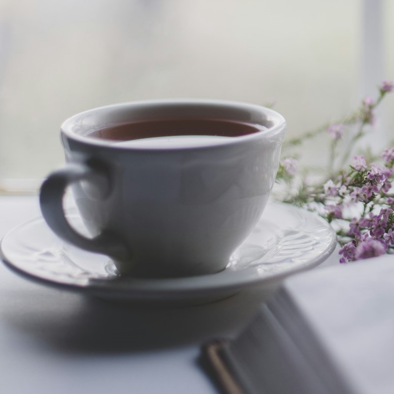 weisse-tasse-tee-mit-teil-von-buch-und-kraeutern