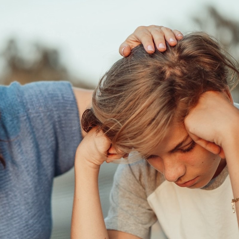 mutter-legt-hand-auf-kopf-des-jungen